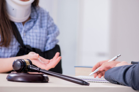 Woman in neck brace and arm sling meeting a lawyer